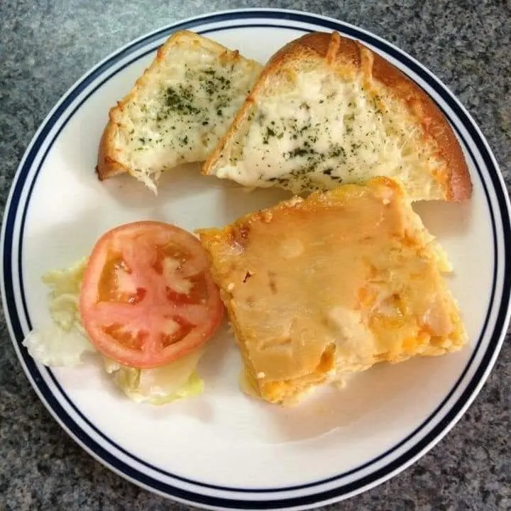Macaroni and cheese with garlic bread and a tomato slice