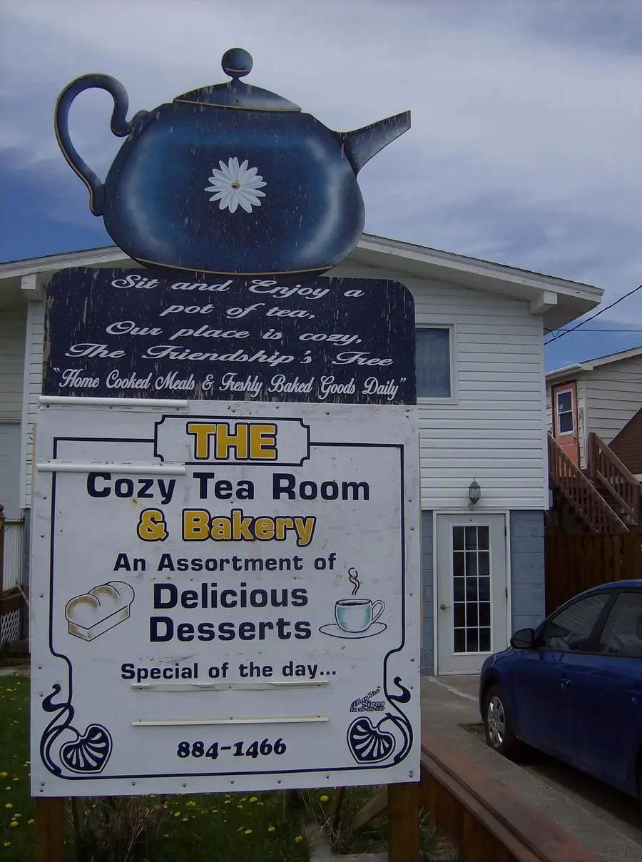 The tea room's storefront sign with a teapot above it, advertising an assortment of desserts